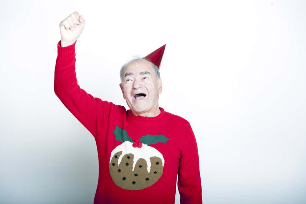 Senior adult man wearing Christmas jumper raising his arm in the air